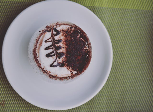 Cappuccino topped with cocoa-dusted latte art on a white plate