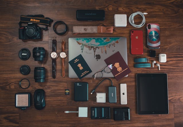 Flat lay of carry-on travel gear including a camera, laptop, passports and gadgets